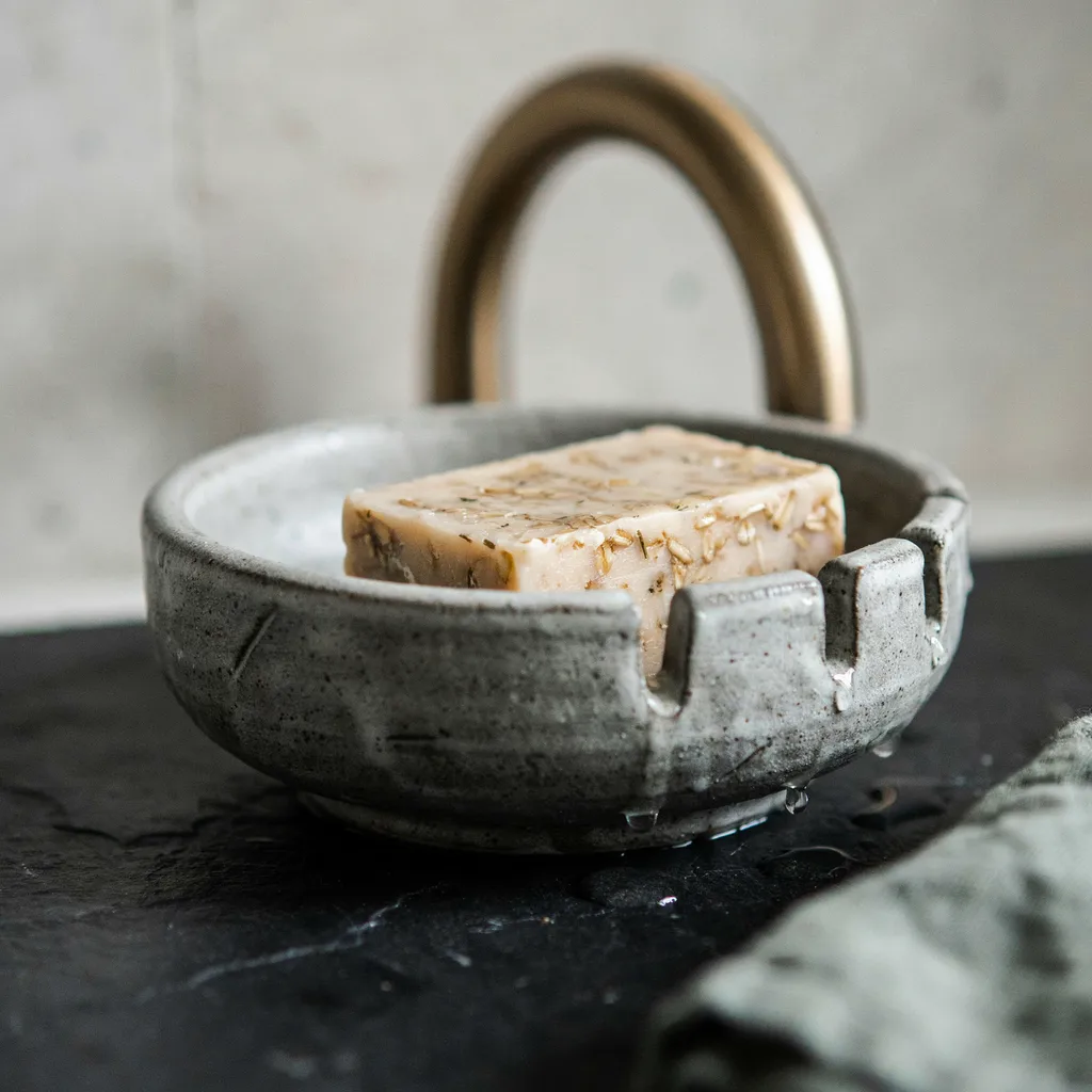 Slotted stoneware soap dish on a sink ledge