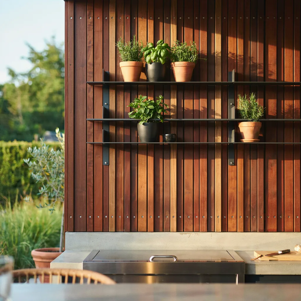 Brazilian Ipe wood slatted accent wall with matte black shelves behind outdoor kitchen grill