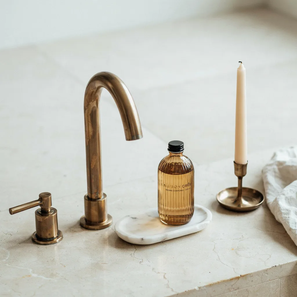 Unlacquered brass faucet and accessories on tub deck